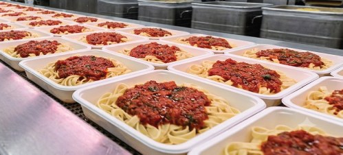 製造ラインで盛り付けられるパスタ