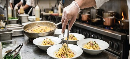 ホテルの厨房でパスタを盛り付けるシェフ